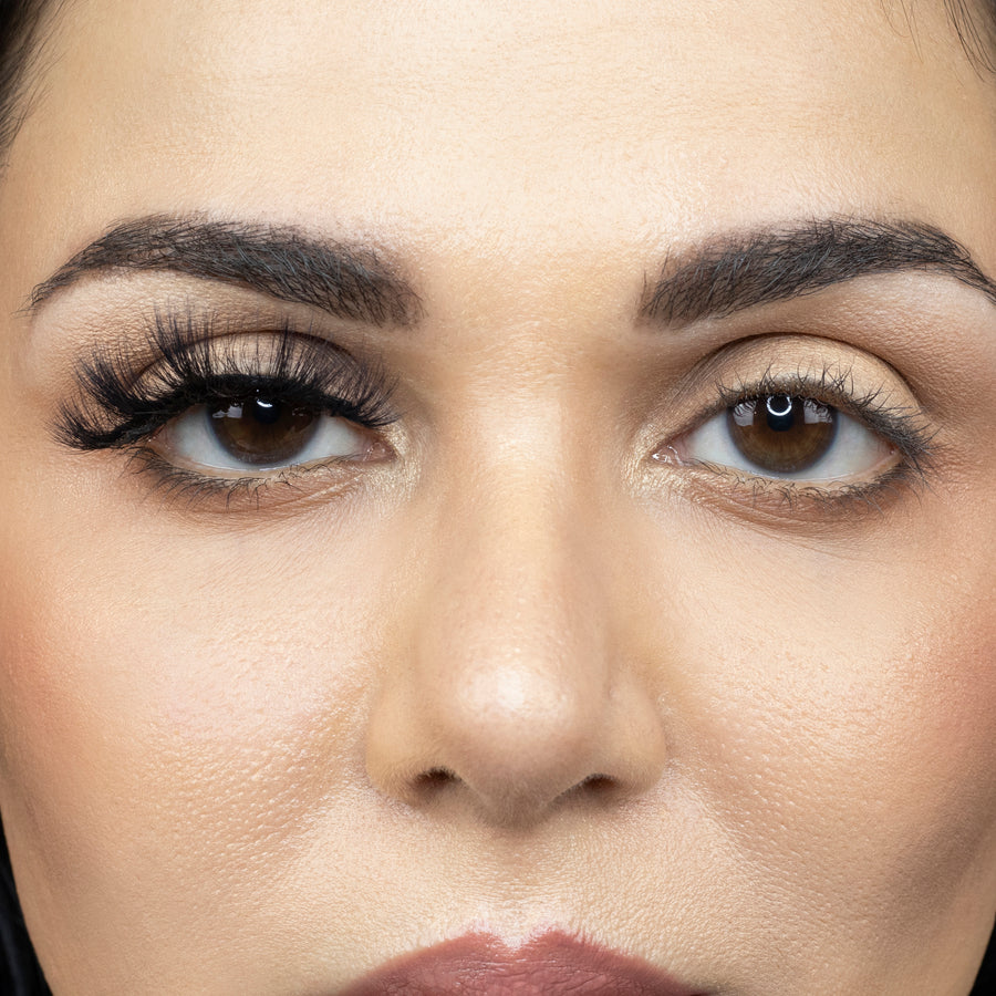 Close up of a young woman looking straight ahead and wearing Suntarah Beauty 3D Faux Mink False strip lash in F-108 on her right eye only. Left eye has no false lash. There is a significant difference in appearance between both eyes. Right eye's lash is beautifully accentuated and has a doll like look.