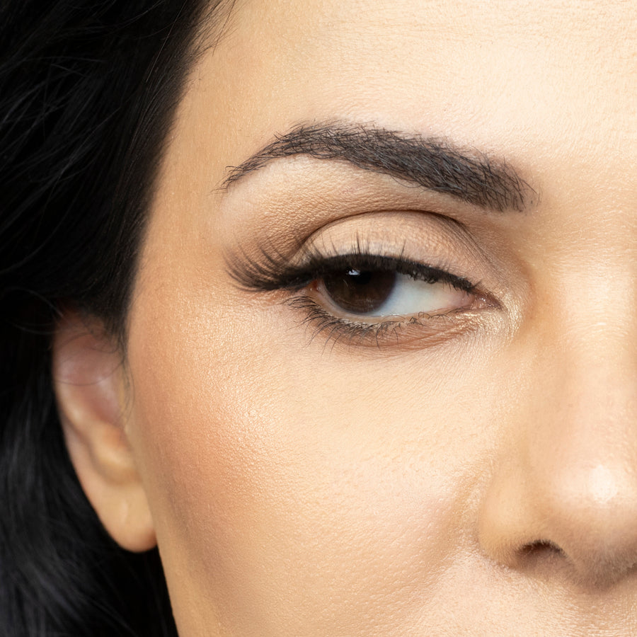 Close up of woman’s right eye while wearing Suntarah Beauty 3D Premium Synthetic false strip eyelash in style S-222.  Woman is looking to the side, showing the slight curl of lash..  