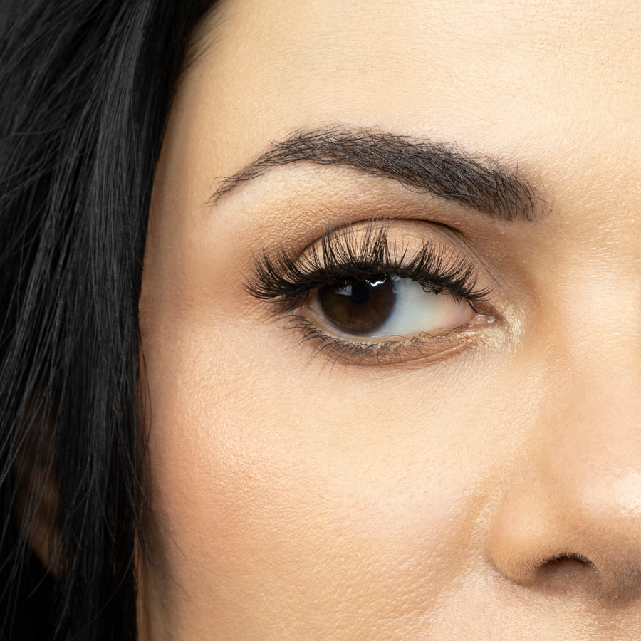 Close up of woman’s right eye while wearing Suntarah Beauty 3D Premium Synthetic false strip eyelash in style S-223.  Woman is looking to the side.  