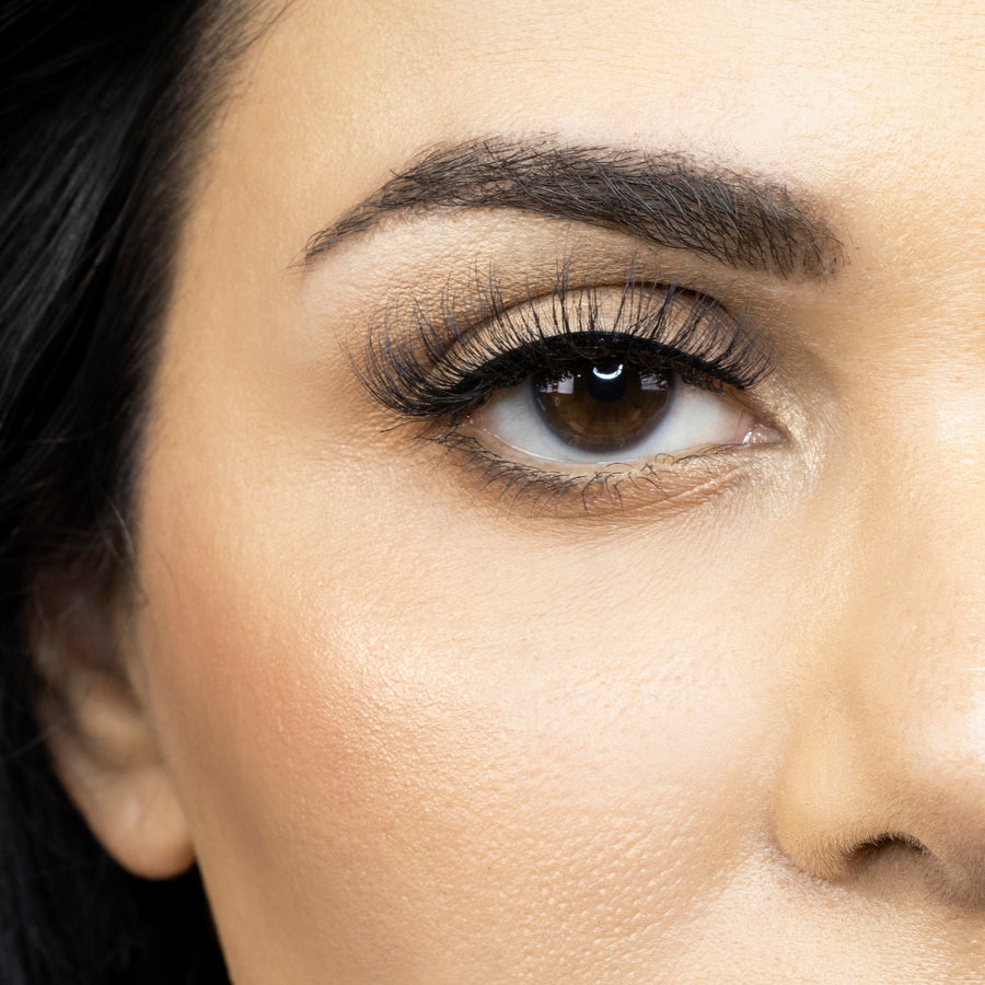 Close up of a young woman's right eye looking straight ahead while wearing Suntarah Beauty's Faux Mink False Strip Lash in style F-102. Lash appears very light and wispy.