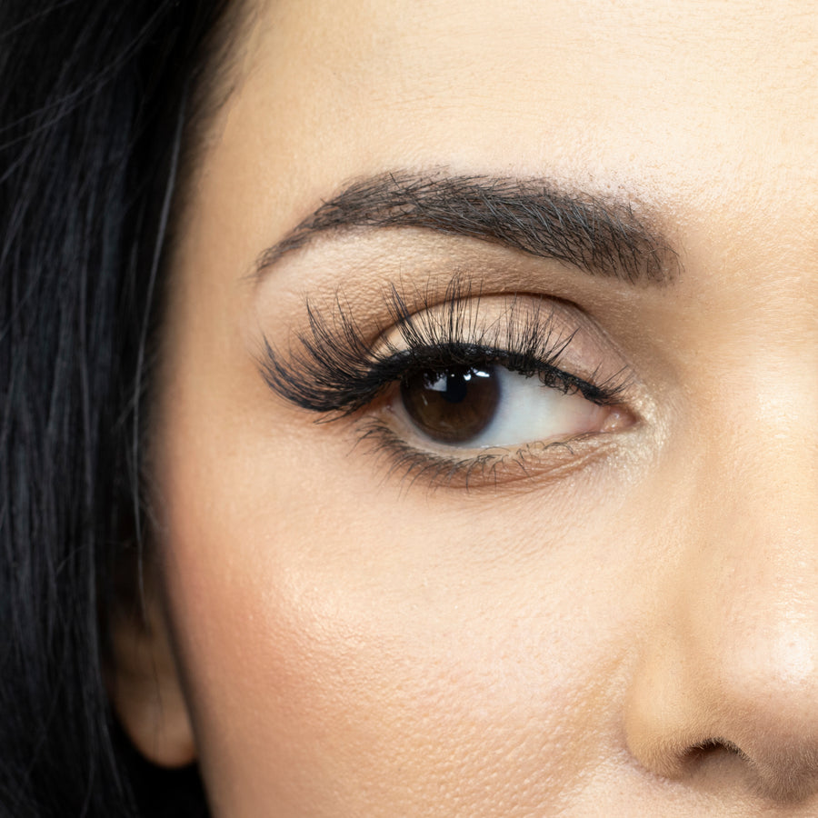 Close up of a young woman's right eye looking to the side and wearing Suntarah Beauty 3D Faux Mink Strip Lash in style F-103. Lash has a light, airy, and wispy look.