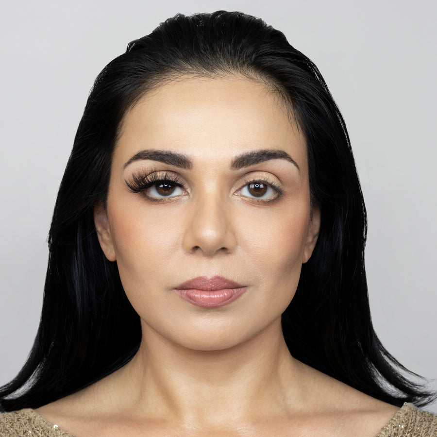Full face of beautiful young woman wearing Suntarah Beauty 3D Faux Mink False Strip Eyelash in Style F-106 on right eye. Image shows a significant difference between appeal of both eyes. Right eye with lash is accentuated and has a glamorous foxy look.