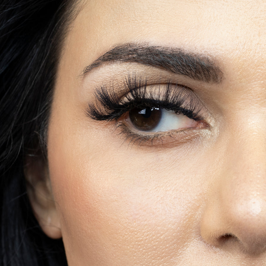 Close up of a young woman's right eye looking to the side and wearing Suntarah Beauty 3D Faux Mink False Strip Lash in F-108. Lash appears dramatic and doll like.