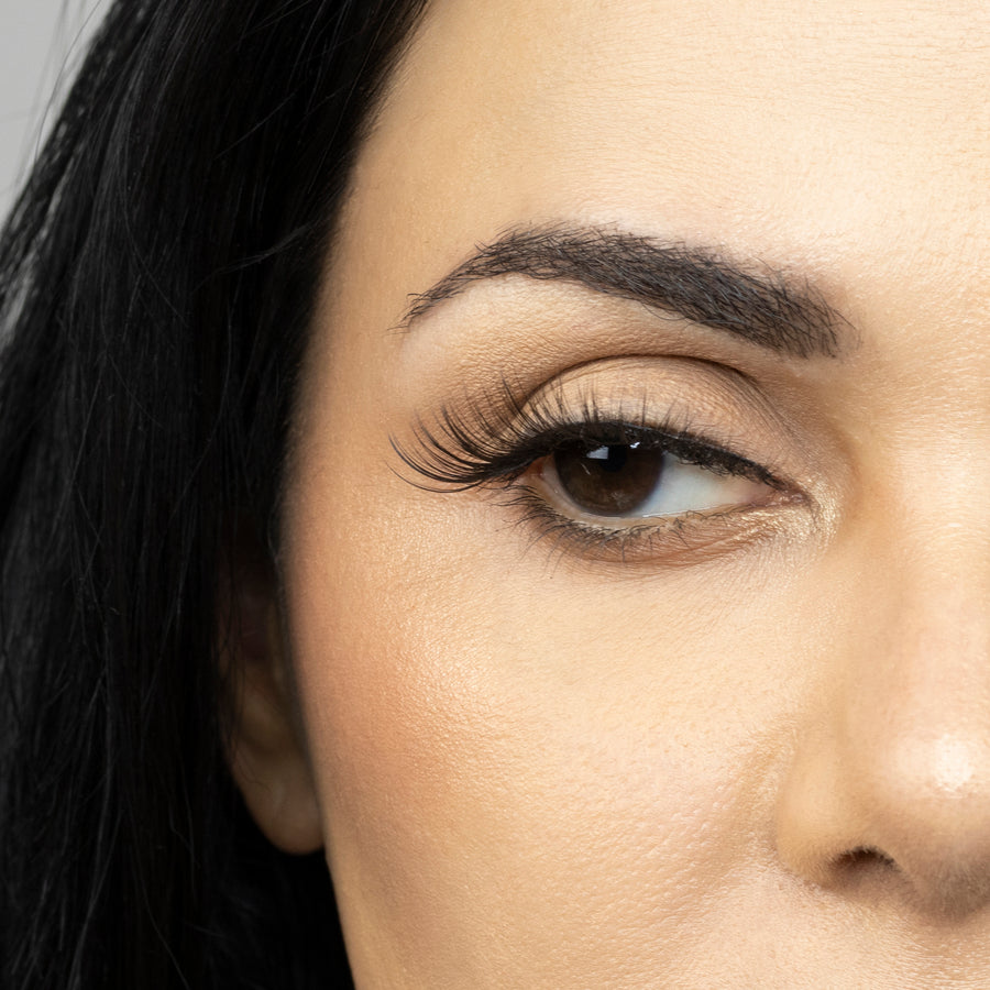 Close up of woman’s right eye while wearing Suntarah Beauty 3D Premium Synthetic false strip eyelash in style S-221.  Woman is looking to the side.  