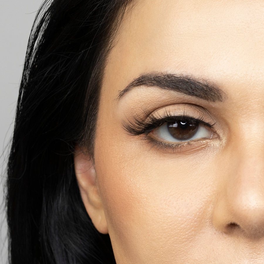 Close up of woman’s right eye while wearing Suntarah Beauty 3D Premium Synthetic false strip eyelash in style S-222.  Woman is looking to the side, showing the slight curl of lash..