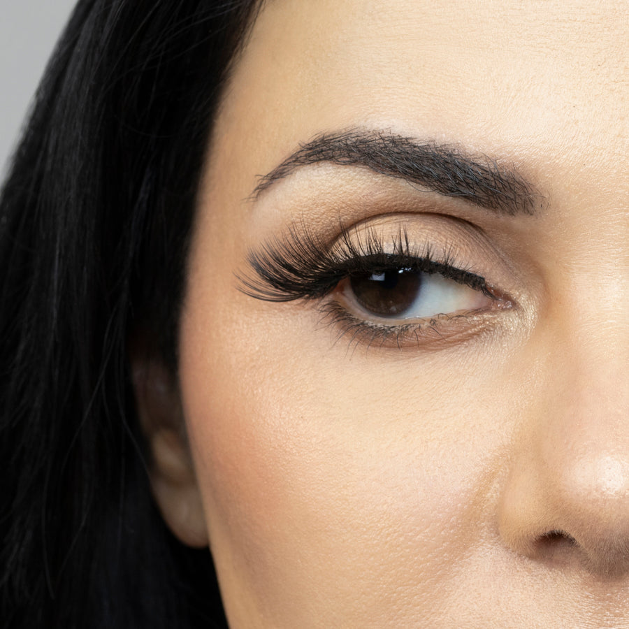 Close up of woman’s right eye while wearing Suntarah Beauty 3D Premium Synthetic false strip eyelash in style S-224. Woman is looking to the side.