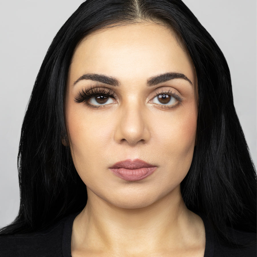 Full face of young beautiful woman wearing Suntarah Beauty Premium Synthetic Strip Eyelash in Style S-225 on right eye only.  There is a significant difference in appeal between both her eyes.  Her right eye is boldly accentuated with a glamorous and dramatic false strip eyelash.