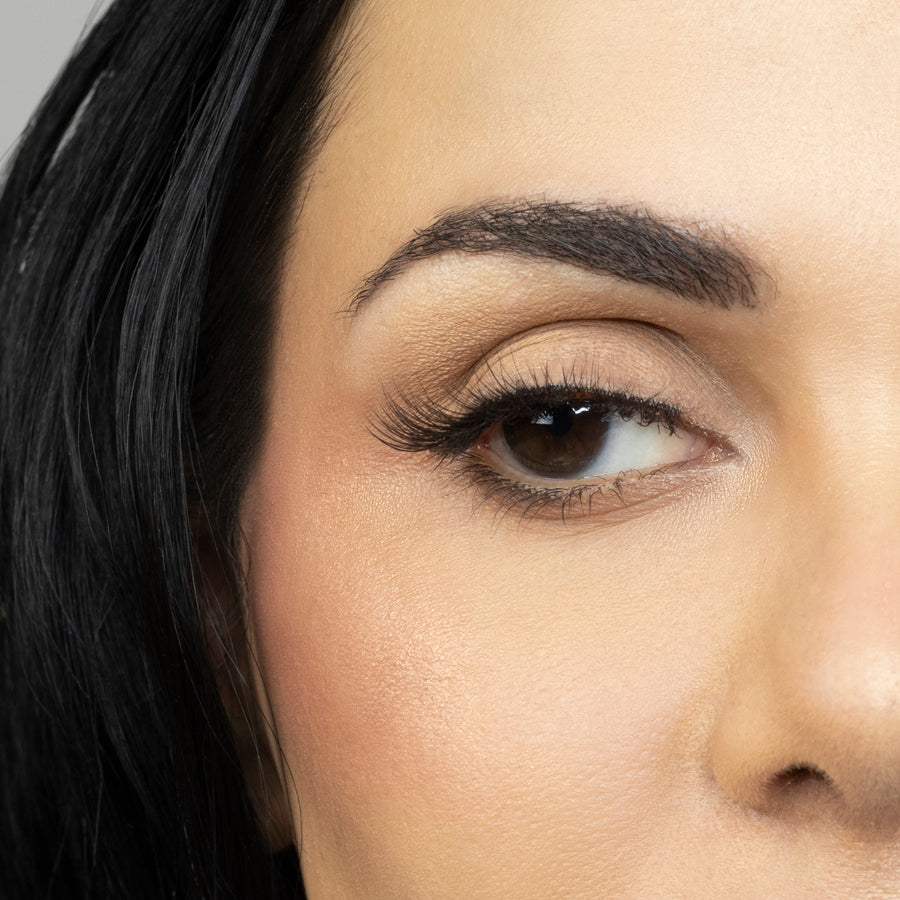 Close up of woman’s right eye while wearing Suntarah Beauty 3D Ultra Light Synthetic false strip eyelash in style SL-332.  Woman is looking to the side.  